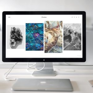 A contemporary office desk setup featuring a sleek computer monitor displaying abstract artwork.